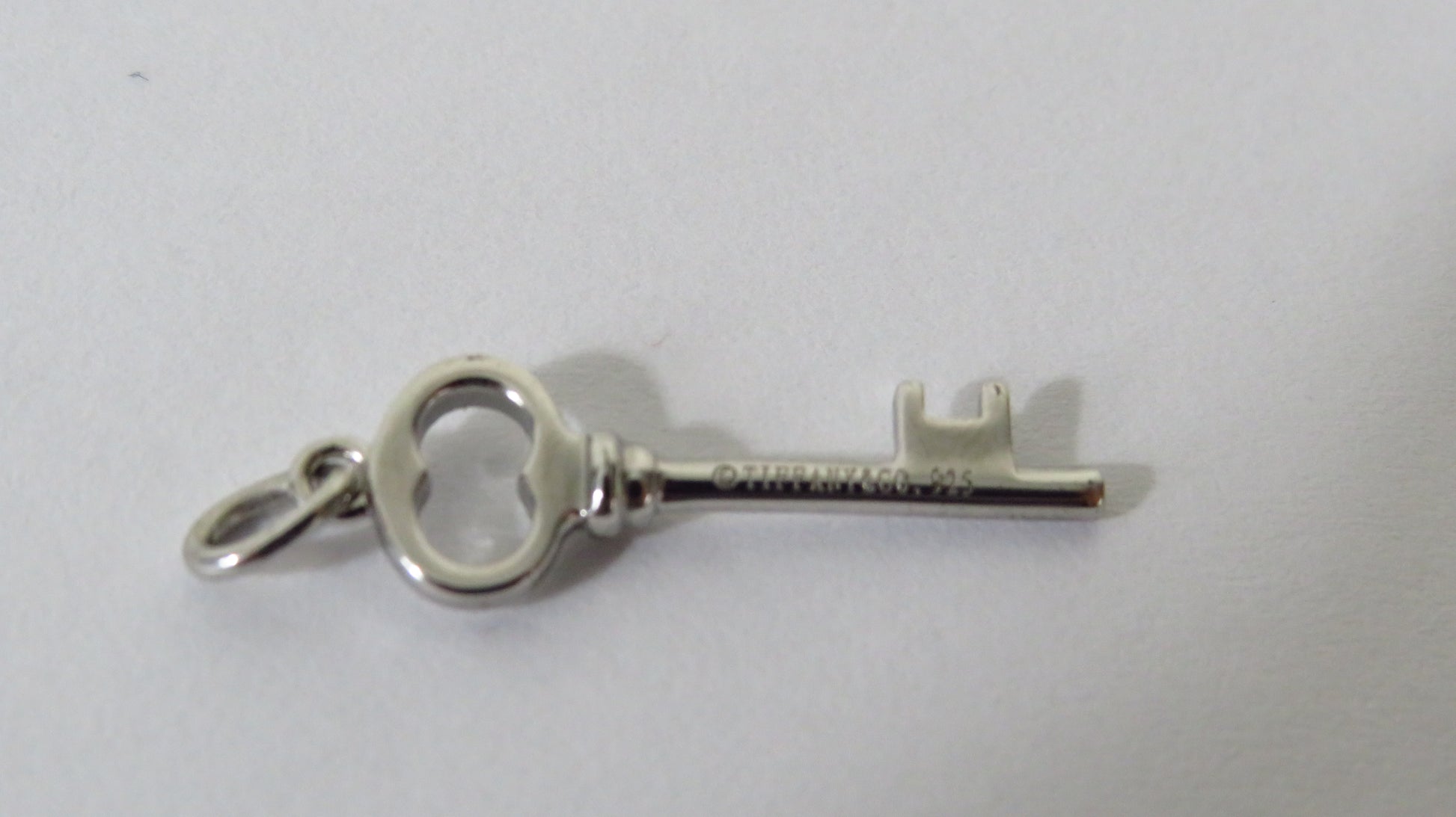 Silver key-shaped pendant on a light gray background