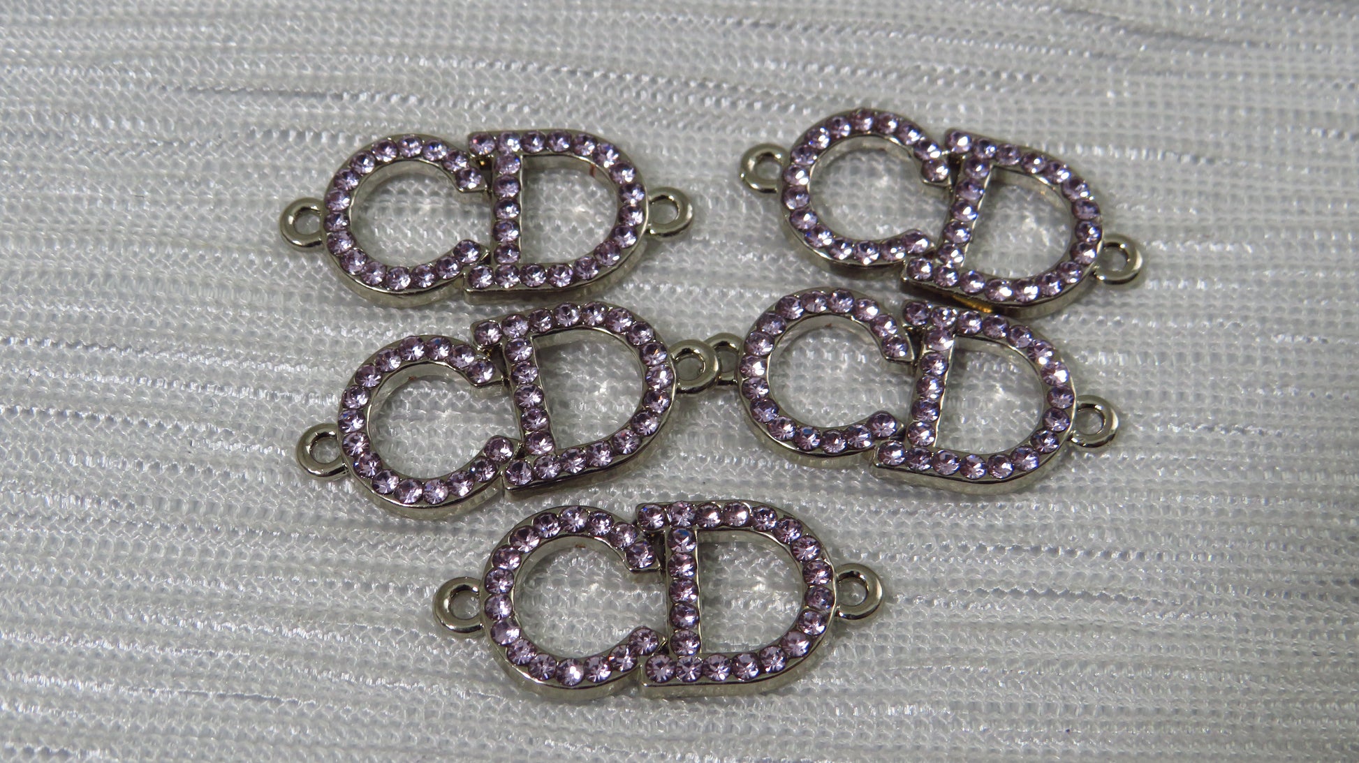 Five purple rhinestone 'CD' connectors on a gray background