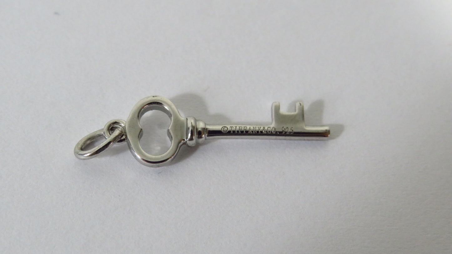 Silver key-shaped pendant on a light gray background