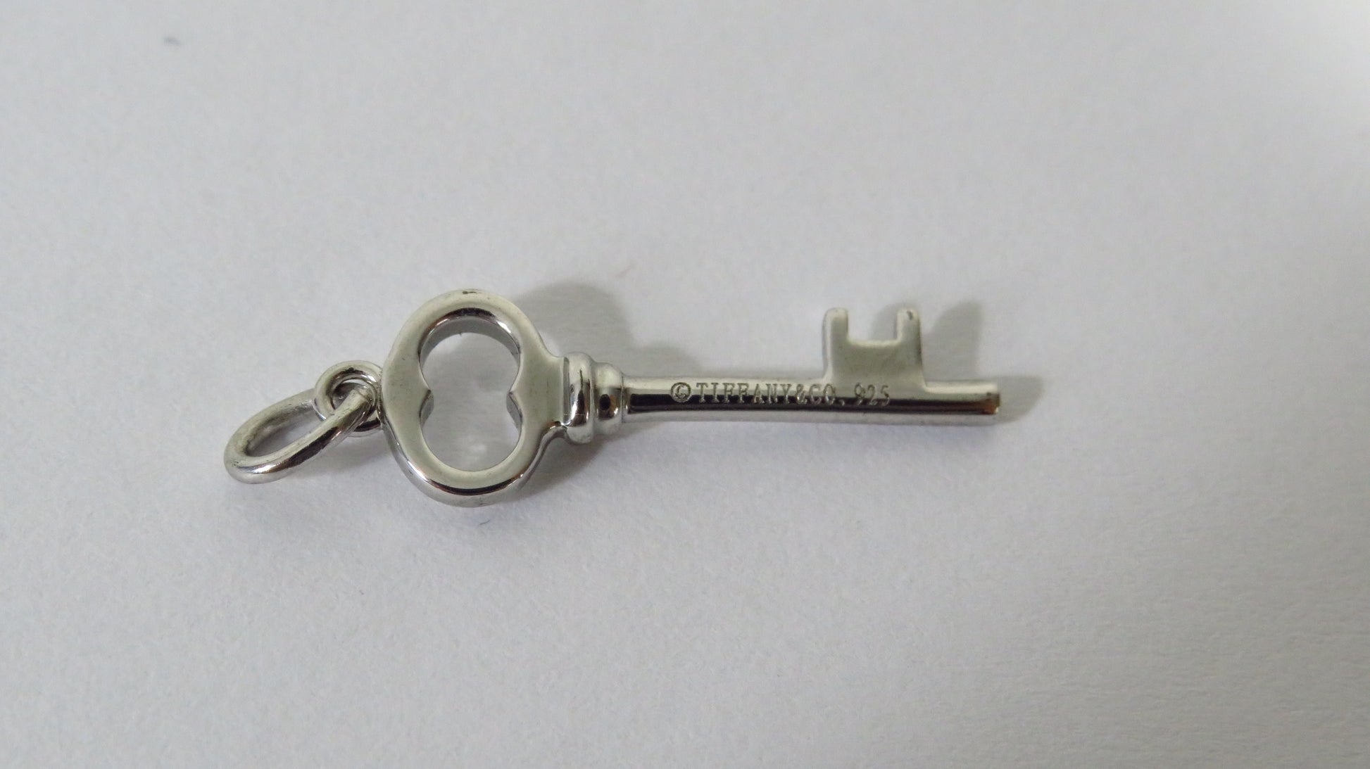 Silver key-shaped pendant on a light gray background