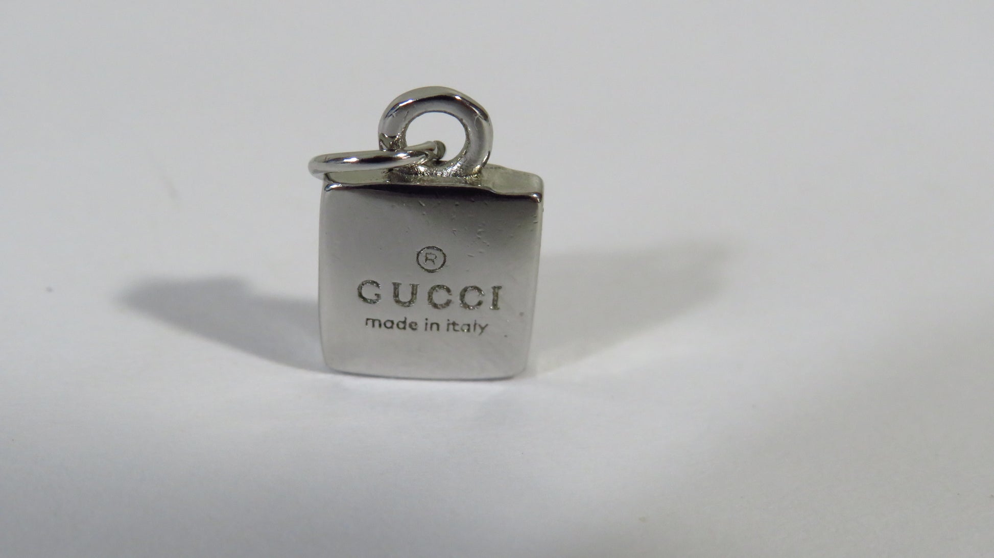 Gucci charm with 'made in Italy' text on a white background