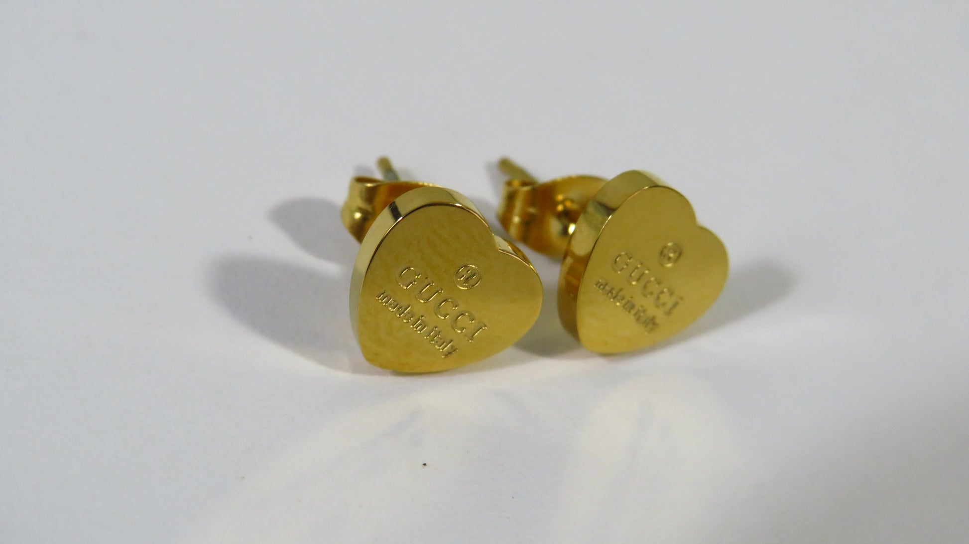 Gold heart-shaped earrings on a white background