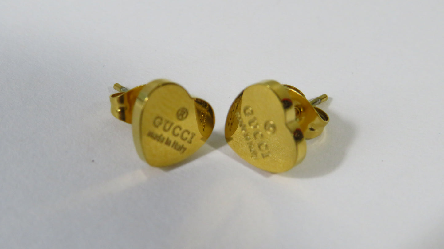 Gold heart-shaped Gucci earrings on a white background