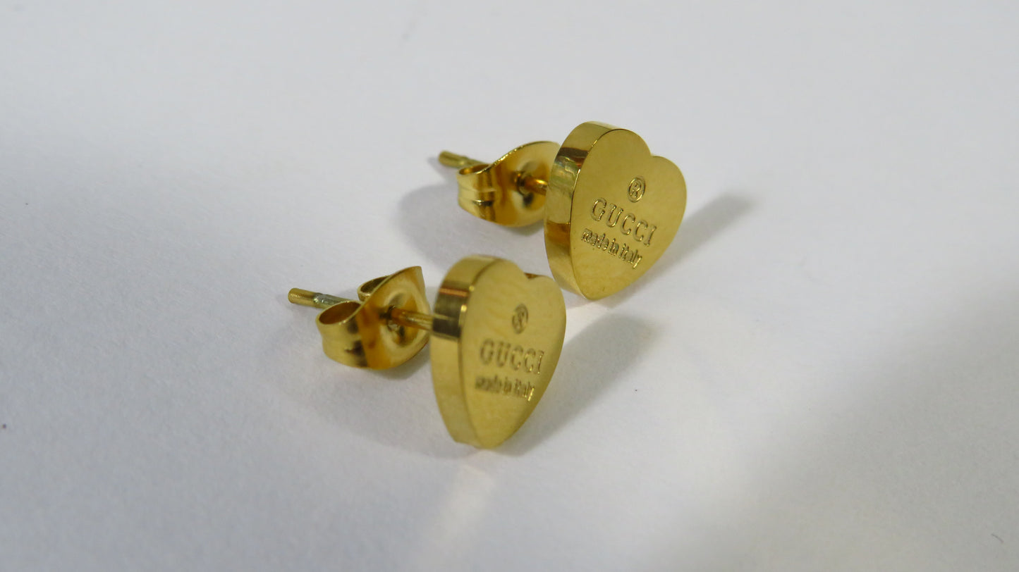 Gold heart-shaped earrings with Gucci logo on a white background