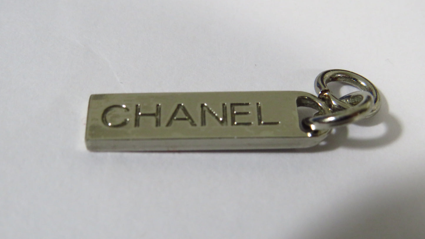 Chanel metal tag charm on a white background