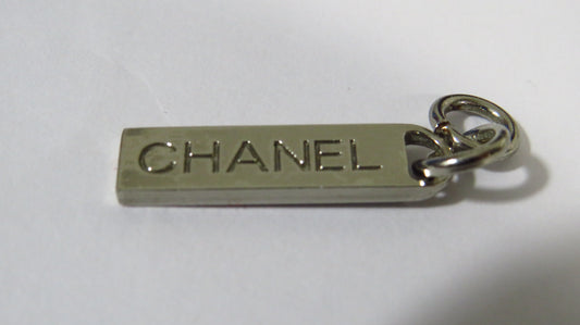 Chanel metal tag charm on a white background