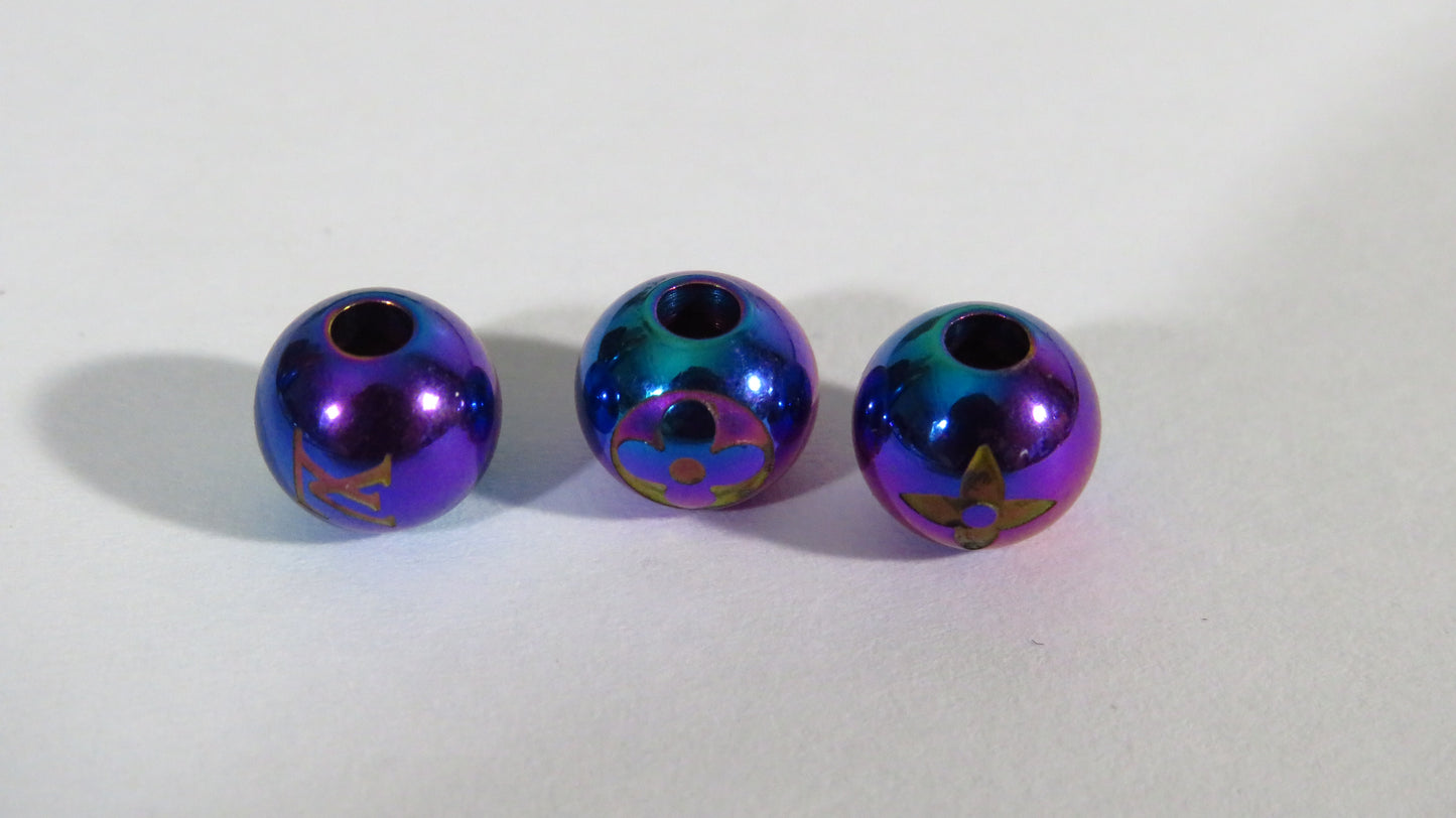 Three metallic beads with a colorful, iridescent finish on a white background