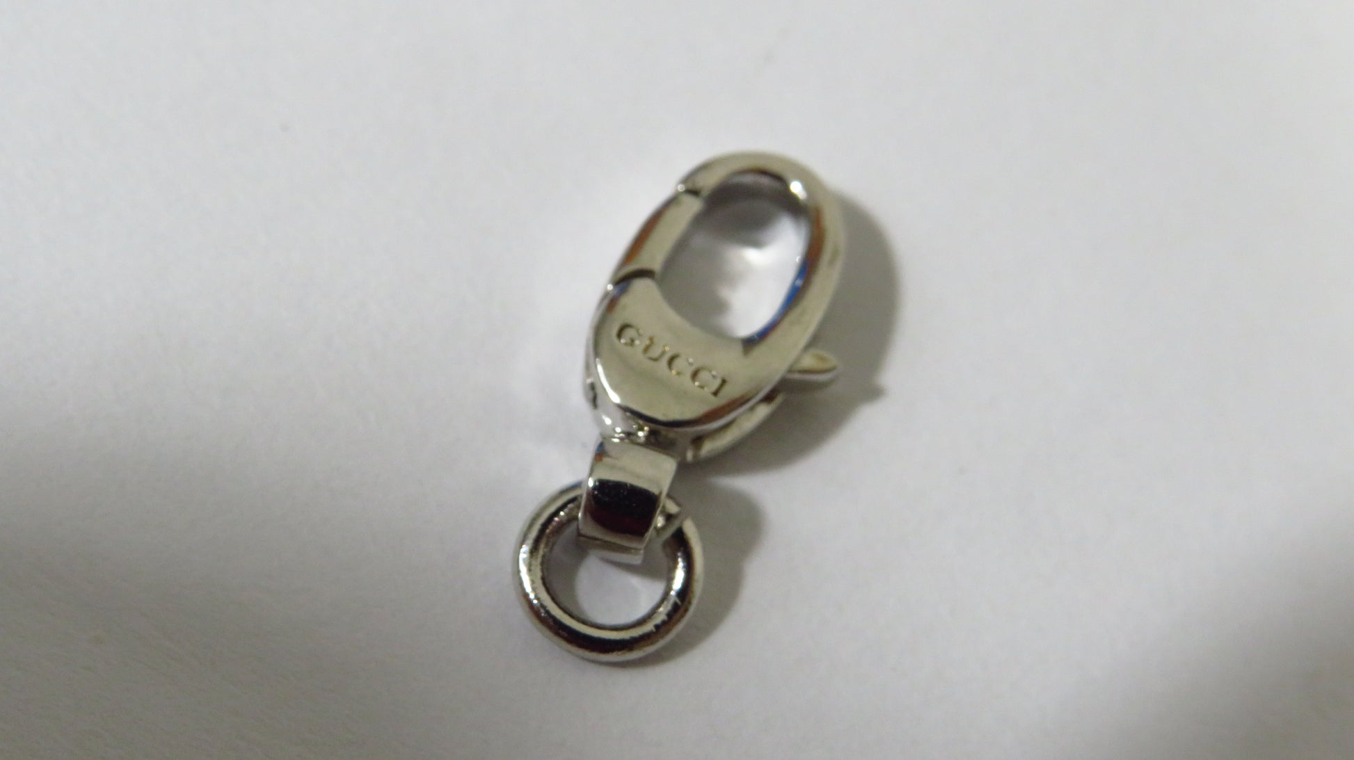 Silver Gucci clasp on a white background