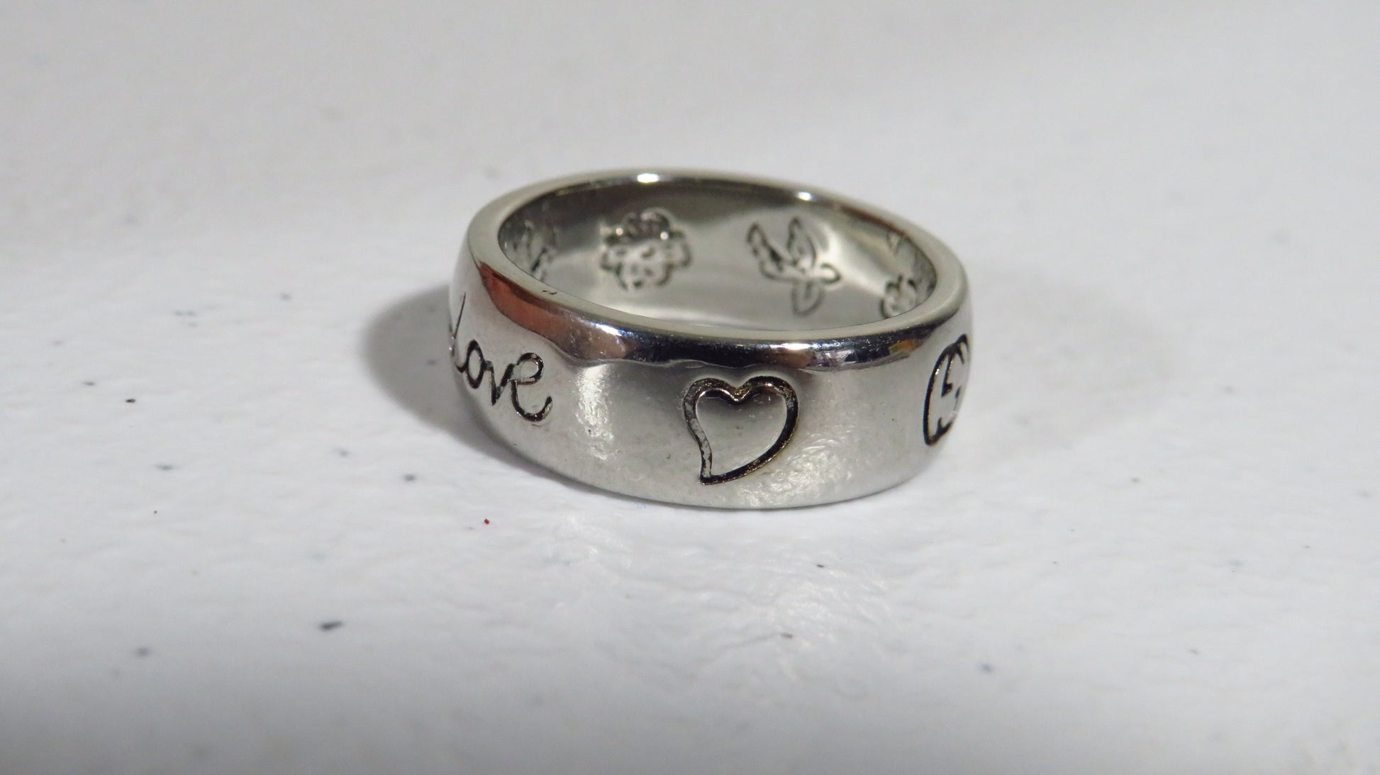 Silver ring with engraved designs on a white background