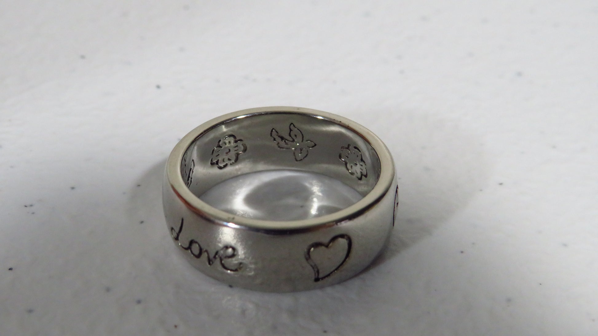 Silver ring with engraved designs on a light gray background