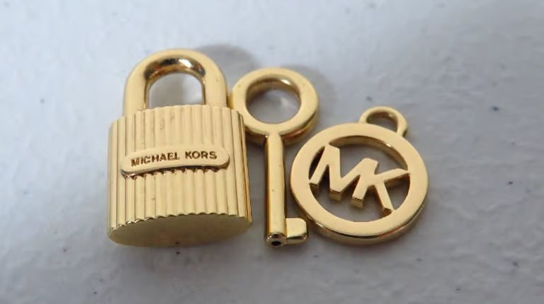 Gold padlock and keychain with 'Michael Kors' branding on a light gray background